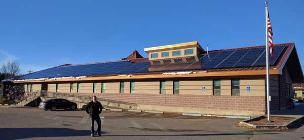 Devin Hawkins stands in front of a solar energy system at the Tribal Capital building in Lame Deer, Montana